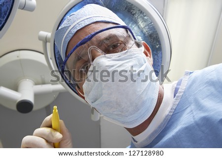 View from below of male surgeon in protective work wear holding an anesthetic during operation
