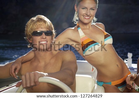 Portrait of friends with arm around while man driving the boat