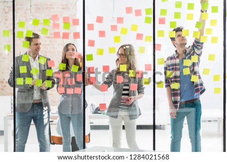 Creative business colleagues using adhesive notes during brainstorming session in office