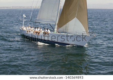 Group of crew members sitting on the side of a sailboat in the ocean