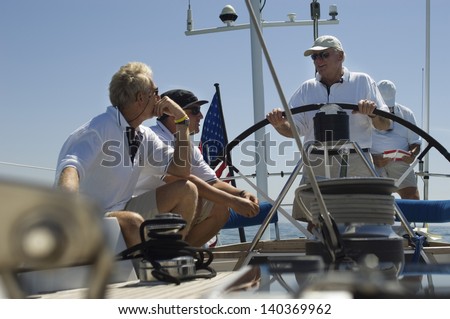 Sailors talking at the helm on a yacht against clear blue sky