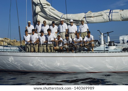 Sailing crew posing for a group portrait on board against clear blue sky