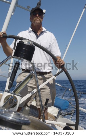 Middle aged man Steering a yacht against clear blue sky