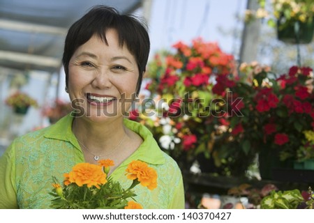 Portrait Of A Smiling Middle Aged Woman With Flowers In Plant Nursery