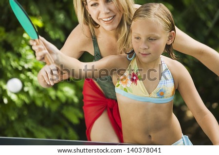Little girl playing ping-pong with her happy mother outdoors