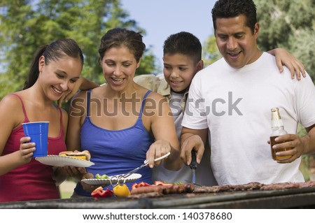 Boy with family gathered around the grill at picnic
