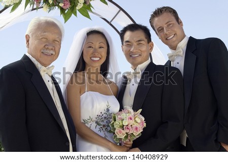 Portrait of newlywed couple with father and best man outdoors