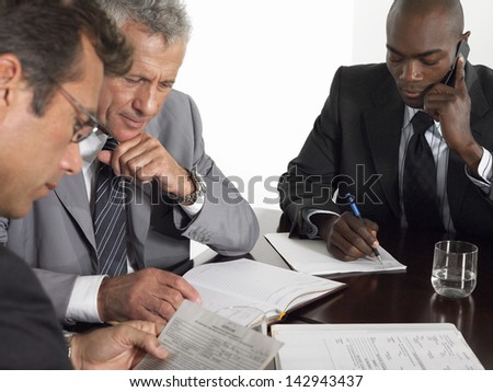 Multiethnic businessmen with paperwork at conference table