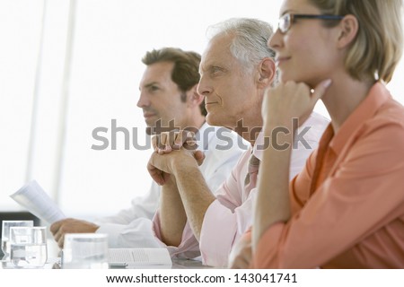 Senior businessman with colleagues paying attention in conference room