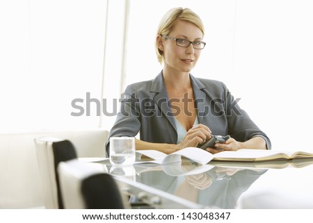 Beautiful businesswoman using mobile phone at conference table