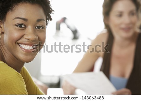 Portrait of smiling African American businesswoman with colleague in background