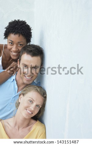 Portrait of happy young multiethnic friends leaning against wall