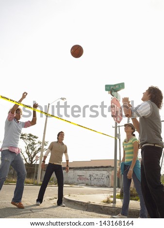 Portrait of smiling young friends playing volleyball over police tape in street