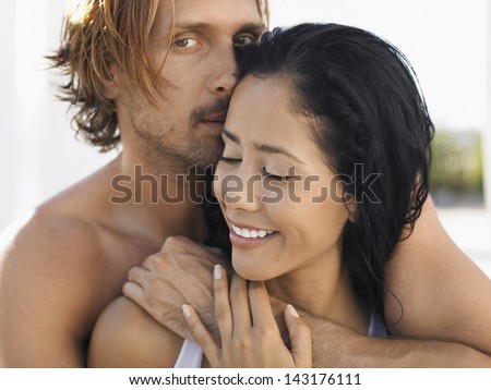 Portrait of romantic young man embracing woman from behind