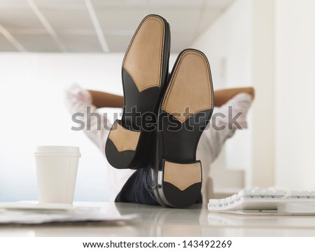 Businessman Reclining With His Feet Up On Computer Desk In Office