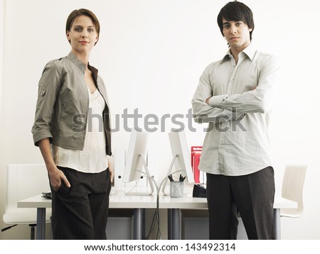 Portrait of multiethnic businessman and businesswoman standing at computer desks