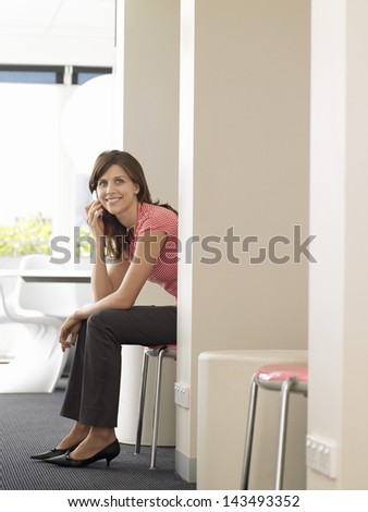 Smiling young businesswoman using cellphone in waiting room