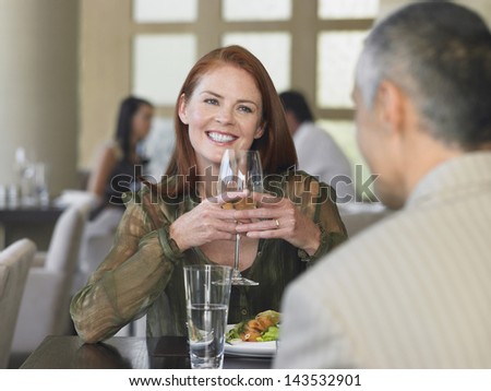 Happy middle aged woman smiling at man over meal in restaurant