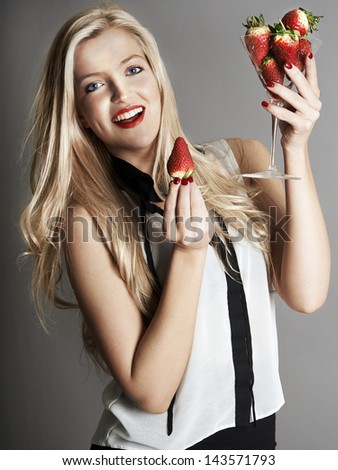 Pretty blonde girl holding glass of Strawberries
