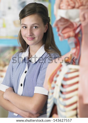 Portrait of high school student standing by anatomical model