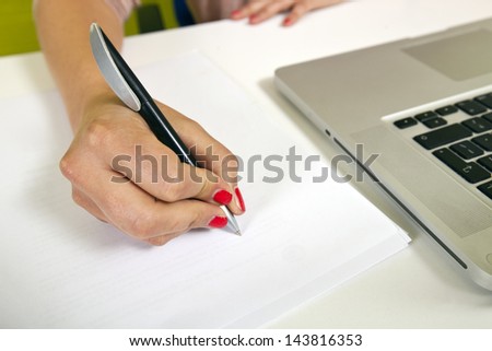 Close-up view of young woman\'s hand writing on paper