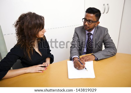 Multi ethnic work colleagues signing paperwork on a table