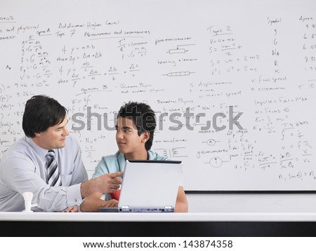 Teacher and student using laptop sitting in physics classroom