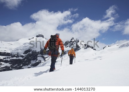 Rear view of two hikers joined by safety line in snowy mountains Rear view of two hikers joined by safety line in snowy mountains