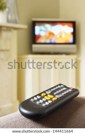 Closeup of a remote control with blurred flat screen television in the background