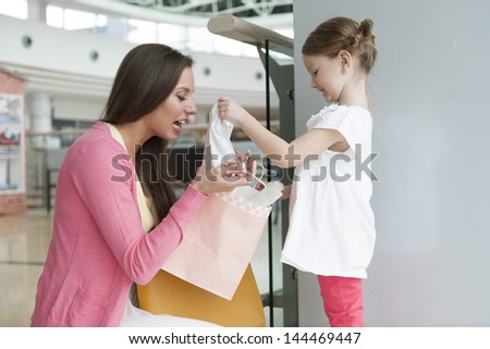 Mother giving daughter gift from paper shopping bag