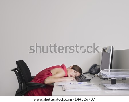 Side view of a female office worker asleep at desk in office