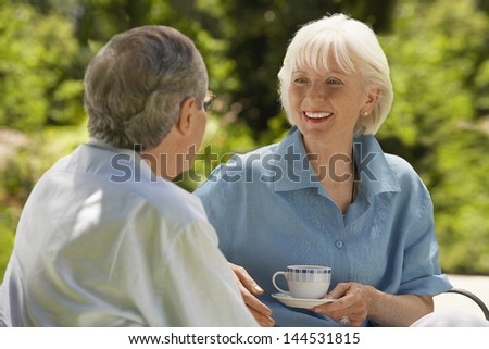 Happy senior woman conversing with husband in backyard
