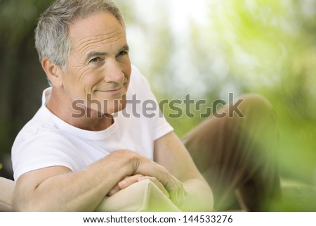 Happy middle aged man reclining on deck chair in garden