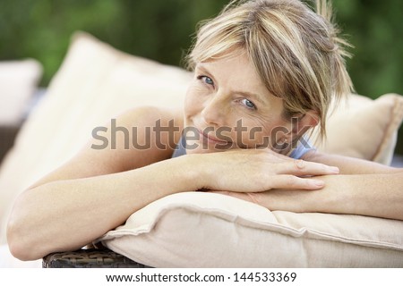 Closeup portrait of happy middle aged woman relaxing on sofa in garden