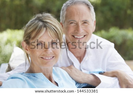 Portrait of happy middle aged couple relaxing in garden