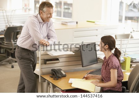 Happy businessman discussing with female colleague at cubicle