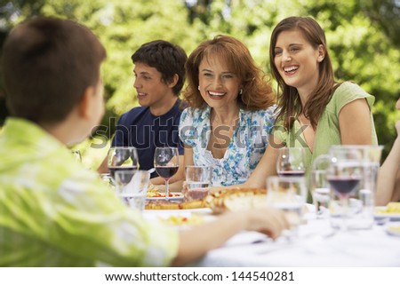 Happy family having lunch together at table in backyard
