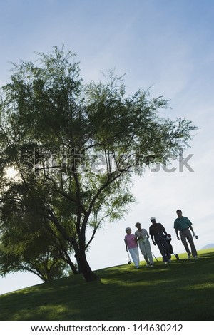 Group of golfers walking by tree on the golf course