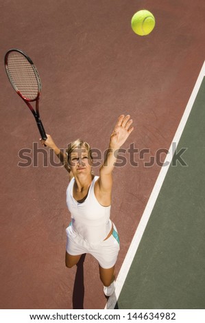 Elevated view of a female tennis player serving ball on court