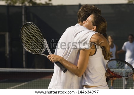 Tennis Players holding rackets Hugging at Net side view