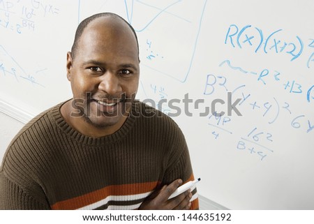 Portrait of a smiling male professor in front of whiteboard with equations
