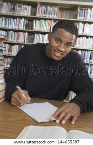 Portrait of an African American male student making notes in the college library