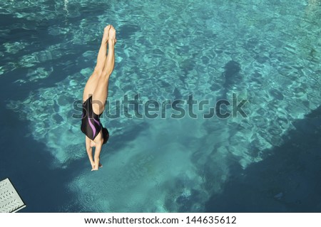 Active female diver diving upside down into the swimming pool