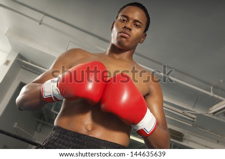 Low angle portrait of a male boxer with red boxing gloves in gym