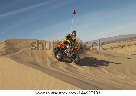 Low angle view of a man riding quad bike in desert on a sunny day