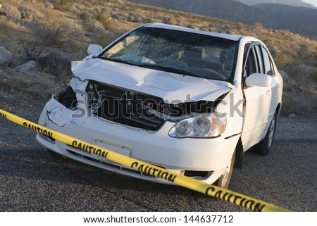 Damaged car behind warning tape at an accident scene