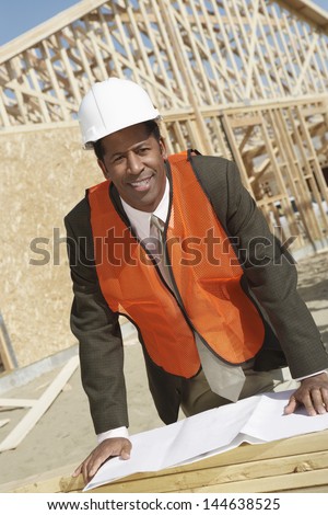 Portrait of a male African American surveyor with blueprints at construction site