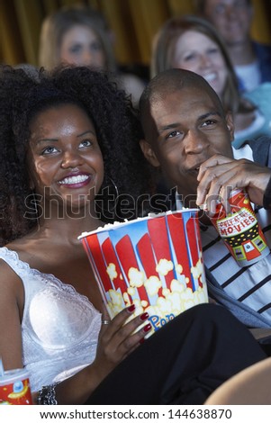 Young happy couple watching movie together in the theatre