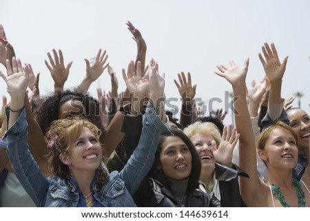 Group of multiethnic women raising hands against clear sky