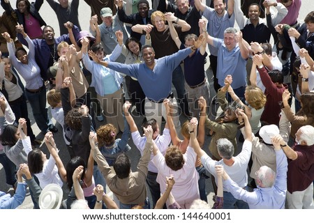 High angle view of cheerful man standing amidst people with hands raised